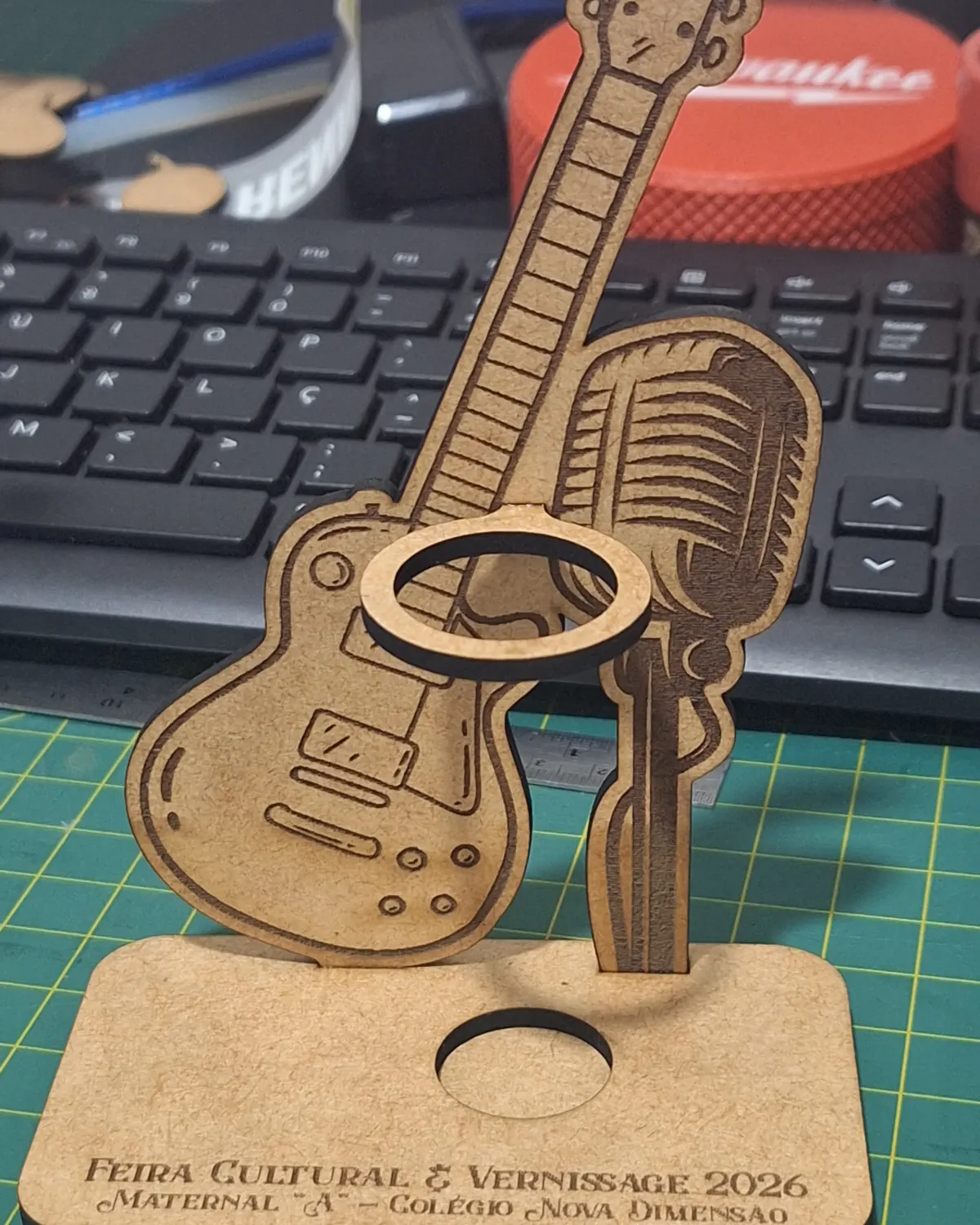 Porta-tubete em MDF com violão e microfone cortados e gravados a laser, sobre a base de corte do estúdio